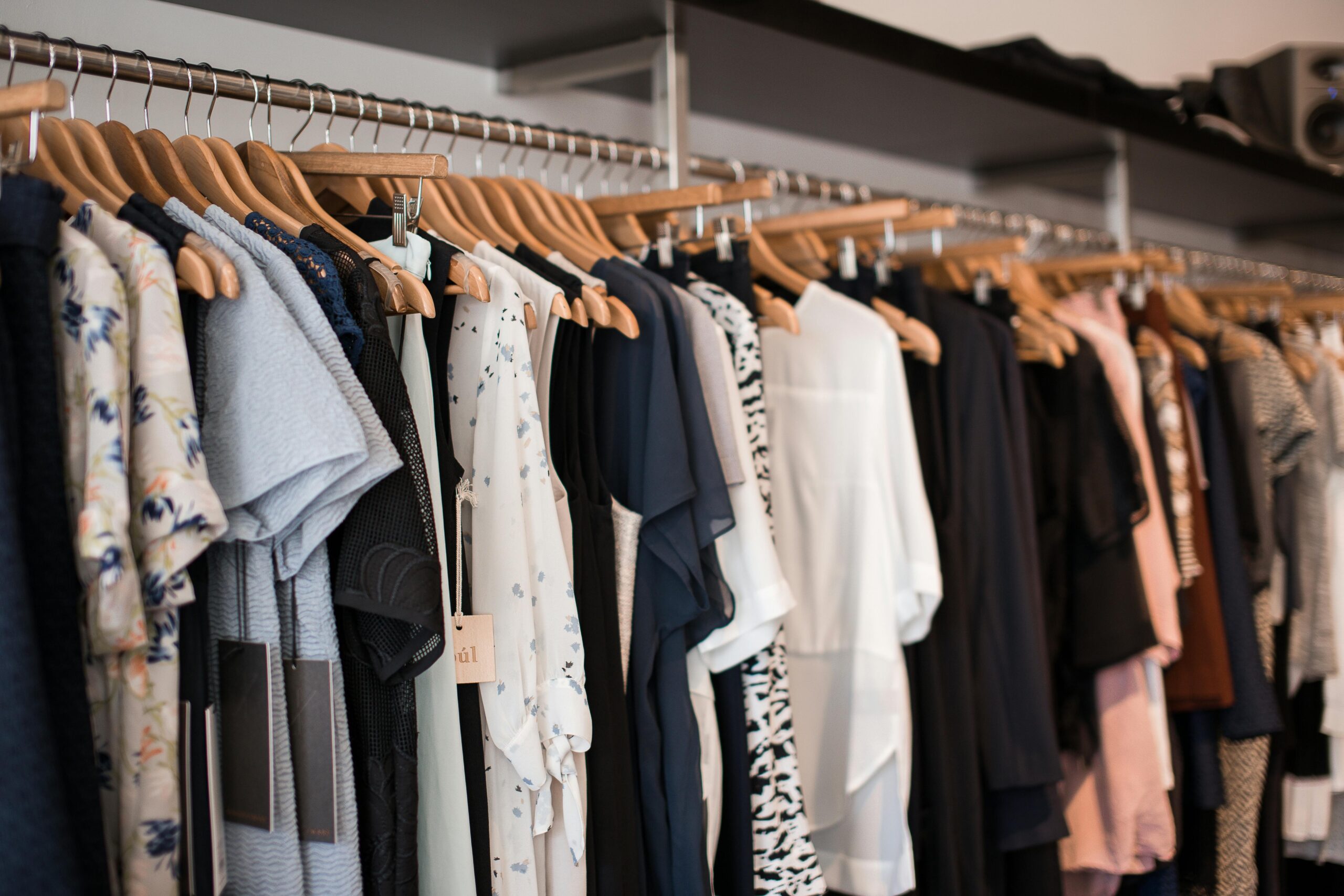 Vibrant clothing display on wooden hangers in a modern boutique setting.